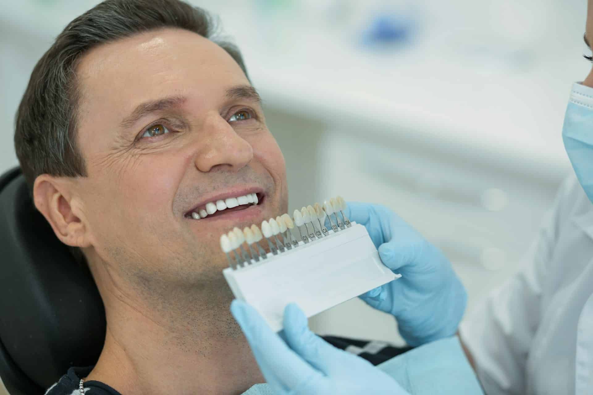 A dentist comparing a patient’s smile with a tooth shade guide