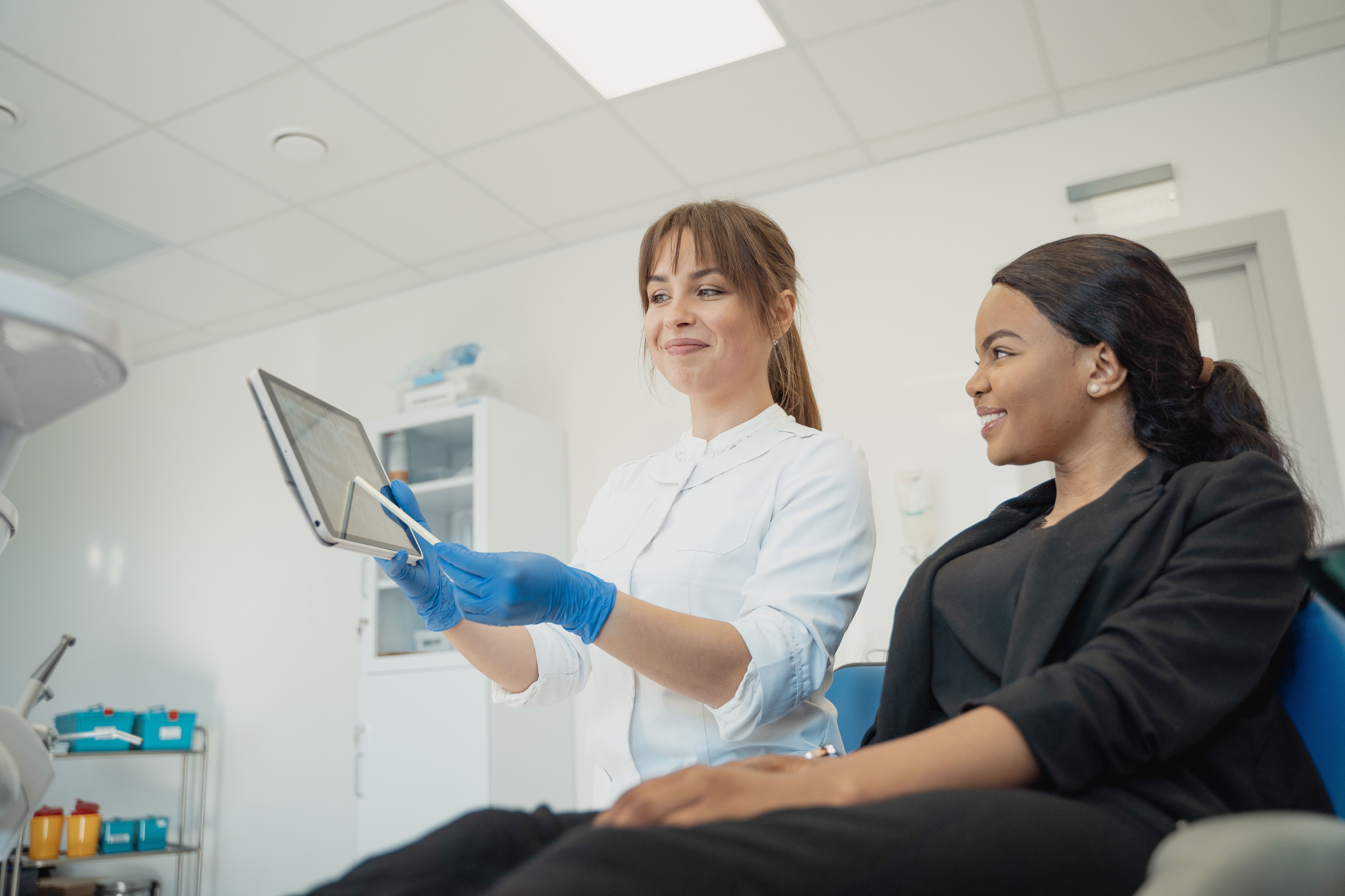 A dental professional reviewing information on a tablet with a patient